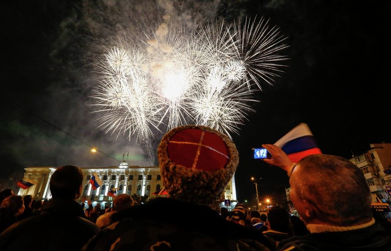Люди наблюдают за праздничным салютом в честь присоединения Крыма к Российской Федерации на главной площади Симферополя Люди наблюдают за праздничным салютом в честь присоединения Крыма к Российской Федерации на главной площади Симферополя