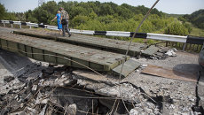 Люди идут мимо разрушенного моста в Донецкой области. Архивное фото Люди идут мимо разрушенного моста в Донецкой области. Архивное фото