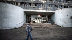 Житель Луганска проходит мимо здания, поврежденного артобстрелом. Архивное фото. Житель Луганска проходит мимо здания, поврежденного артобстрелом. Архивное фото.