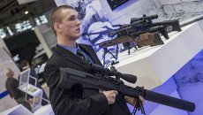 Сотрудник со снайперской крупнокалиберной бесшумной винтовкой Выхлоп на стенде компании Ростех на международной выставке Интерполитех-2015 в Москве Сотрудник со снайперской крупнокалиберной бесшумной винтовкой Выхлоп на стенде компании Ростех на международной выставке Интерполитех-2015 в Москве