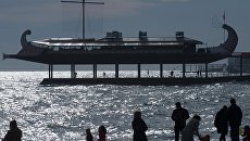 Отдыхающие гуляют вечером по пляжу у одного из ресторанов в виде галеры на набережной Ялты. Архивное фото Отдыхающие гуляют вечером по пляжу у одного из ресторанов в виде галеры на набережной Ялты. Архивное фото