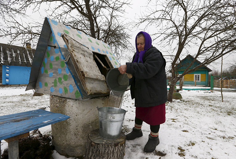 Женщина набирает воду из колодца в Белоруссии Женщина набирает воду из колодца в Белоруссии