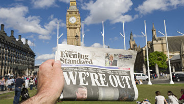 Мужчина держит в руке газету у здания парламента в Лондоне после референдума по сохранению членства Великобритании в Европейском Союзе