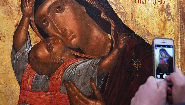Посетитель фотографирует икону Богоматерь с младенцем. Архивное фото