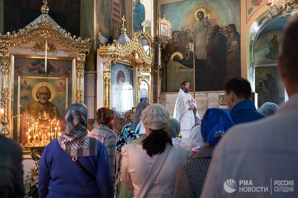 Священнослужитель и верующие во время богослужения в честь праздника Преображения Господня в соборе Воздвижения Креста Господня в Омске. 19 августа 2017 Священнослужитель и верующие во время богослужения в честь праздника Преображения Господня в соборе Воздвижения Креста Господня в Омске. 19 августа 2017