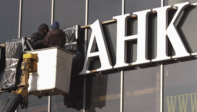 Рабочие завешивают вывеску с названием банка в Москве Рабочие завешивают вывеску с названием банка в Москве