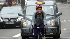 Девушка едет на велосипеде по улице Лондона. Архивное фото Девушка едет на велосипеде по улице Лондона. Архивное фото
