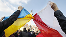Люди держат связанные флаги Польши и Украины в Варшаве. Архивное фото Люди держат связанные флаги Польши и Украины в Варшаве. Архивное фото