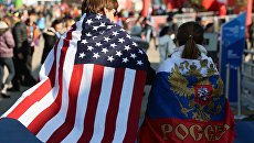 Молодые люди в национальных флагах США и России. Архивное фото Молодые люди в национальных флагах США и России. Архивное фото