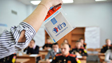 Преподаватель демонстрирует пакет и компакт-диск с заданиями перед началом ЕГЭ Преподаватель демонстрирует пакет и компакт-диск с заданиями перед началом ЕГЭ