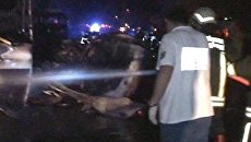 Пожарные заливают водой горящие после взрыва машины Пожарные заливают водой горящие после взрыва машины